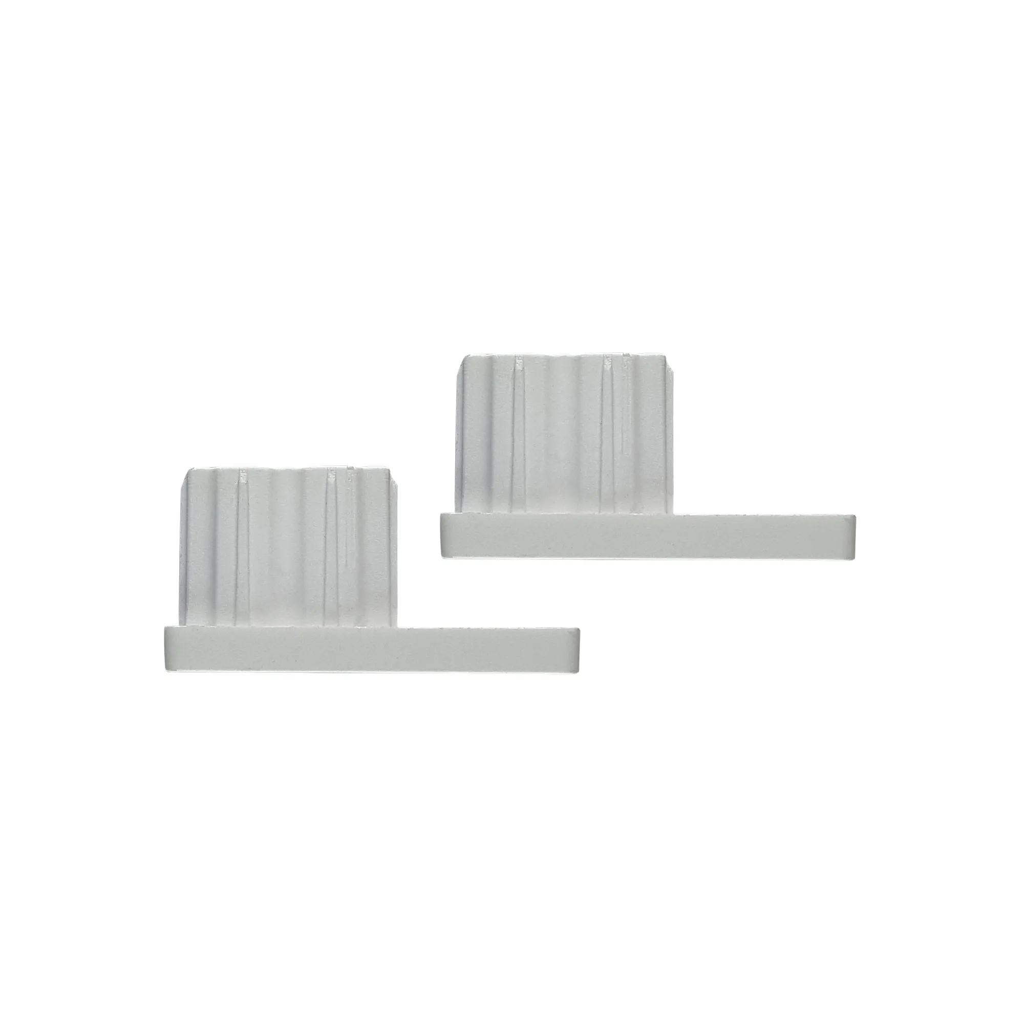 Due pezzi rettangolari in plastica con scanalature verticali e base orizzontale